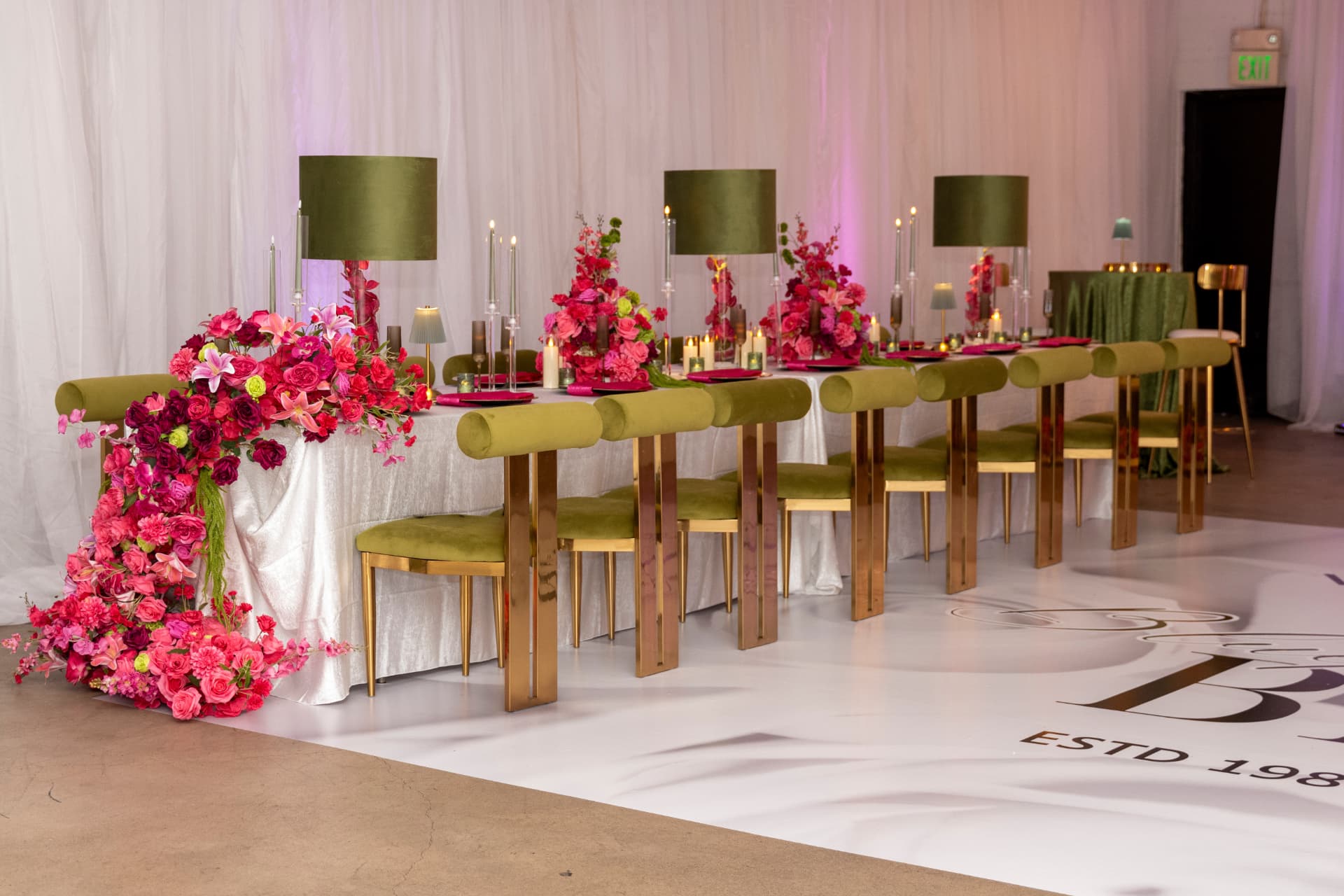 Long guest table with cascading florals, olive velvet chairs and a printed monogram floor