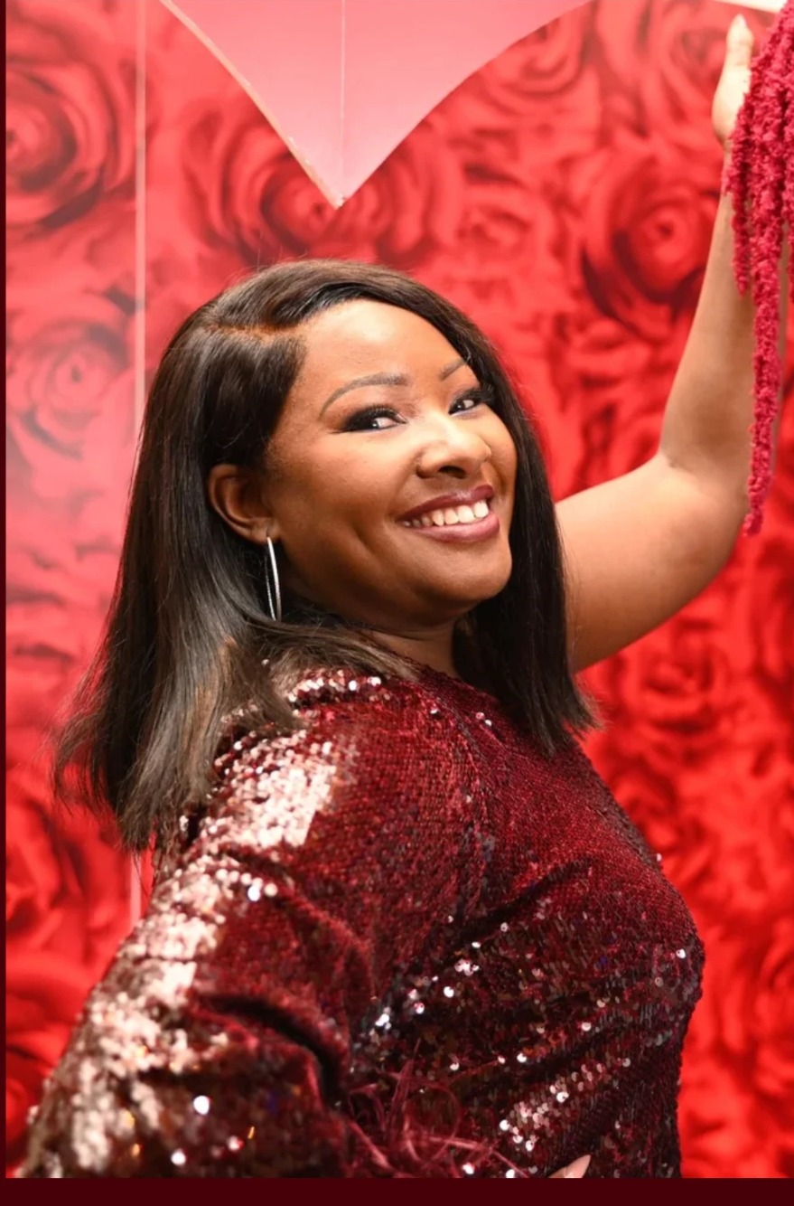 Crystal Brown, founder of Intent Design Studio, in front of a red rose wall